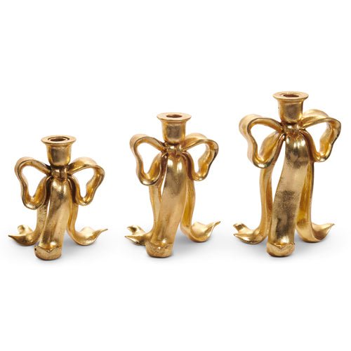 Set of three gold bow candlesticks in assorted heights, made of resin and iron, designed for taper candles.