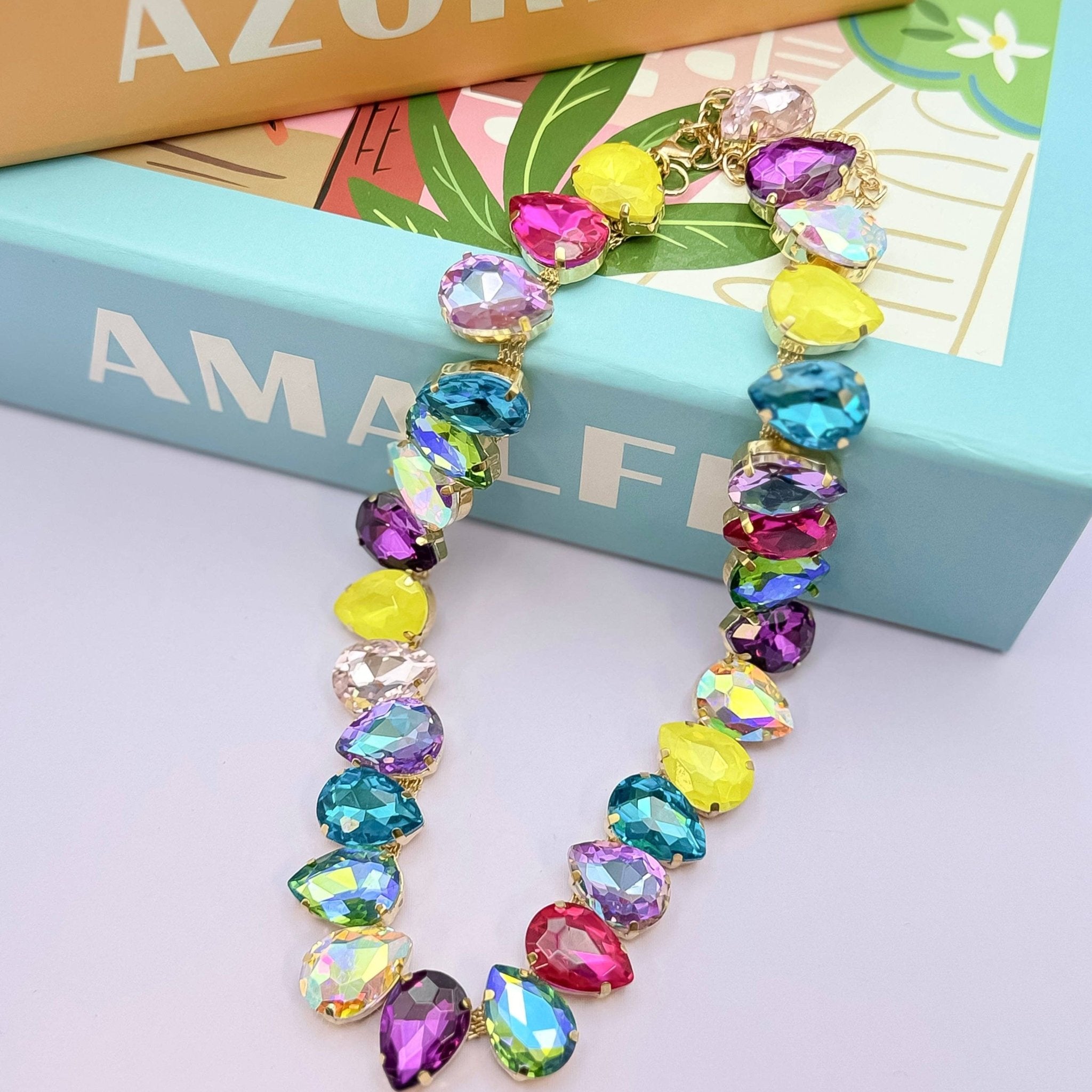 Colorful beaded necklace on a light purple surface with a book in the background