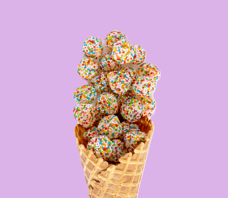 Waffle cone filled with colorful ice cream balls on a purple background