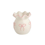 White ceramic bud vase with pink bows and ruffled edge.