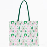 Tote bag with festive design featuring pink elves, green wreaths, and red doors on a light background.