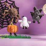 Halloween-themed plush toys including a spider, ghost, and bat on a purple background with a spider web and moon.