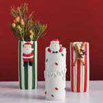 White ceramic bud vase with Santa figurine and Christmas lights detail.
