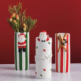 White ceramic bud vase with Santa figurine and Christmas lights detail.