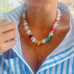 Colorful beaded necklace with a gold chain worn by a person in a striped shirt.