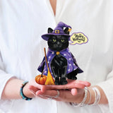 Hands holding a mini Halloween pop-up card featuring a black cat in a purple witch costume with a pumpkin and broom