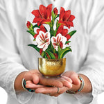 Hands holding a pop-up bouquet of red and white mini amaryllis in a gold bowl
