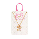 "Gold chain necklace with pink enamel bow charm on polka dot display card for kids