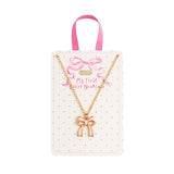 "Gold chain necklace with pink enamel bow charm on polka dot display card for kids