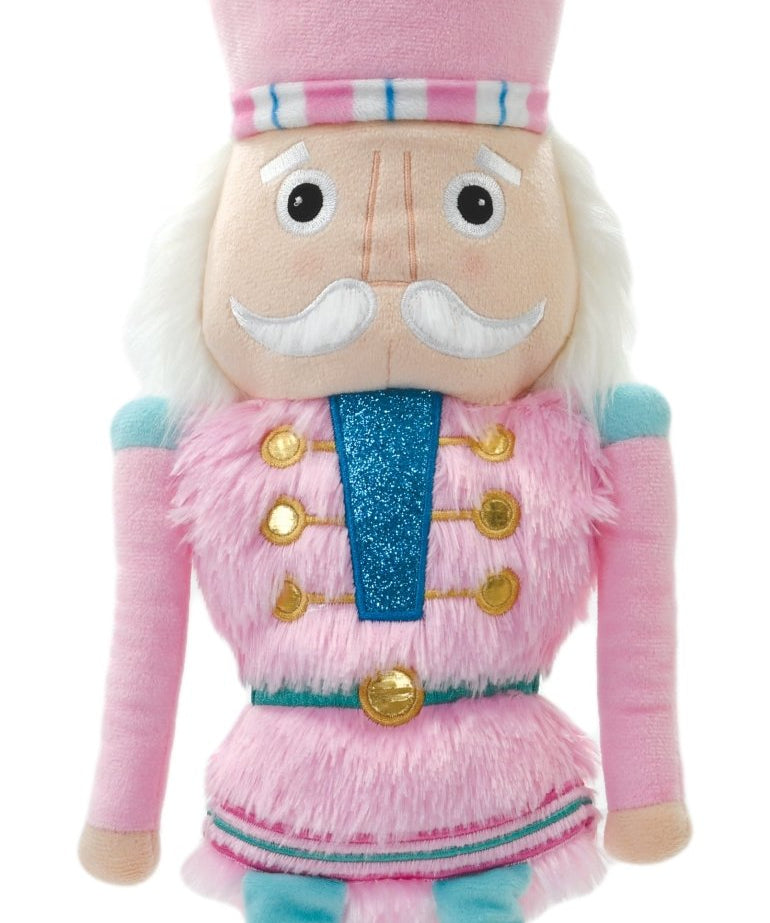 Pink Nutcracker plush ornament with faux fur, fleece, metallic embroidery, and hanging loop, measuring 7 inches tall.