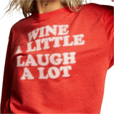 Model wearing red “Wine A Little, Laugh A Lot” fitted sweatshirt with retro text and ribbed cuffs