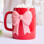 Red ceramic mug with sculpted pink bow by Mary Square, perfect for holiday drinks.