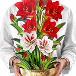 Woman holding a tall pop-up bouquet of red and white amaryllis flowers in a gold hammered bowl