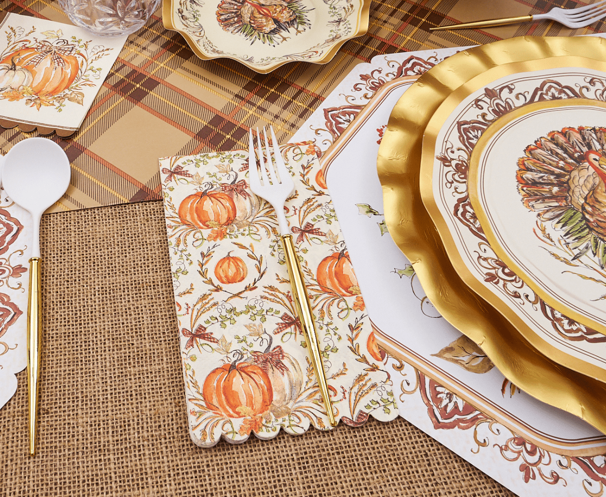 Thanksgiving-themed table setting with gold plates, pumpkins, and burlap placemats.