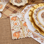 Thanksgiving-themed table setting with gold plates, pumpkins, and burlap placemats.