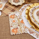 Thanksgiving-themed table setting with gold plates, pumpkins, and burlap placemats.
