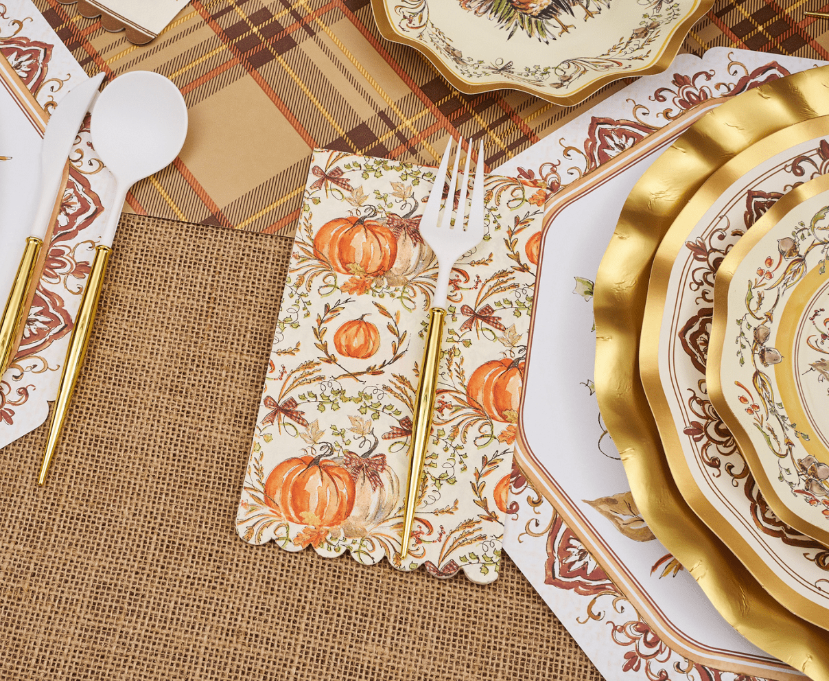 Thanksgiving-themed table setting with gold plates, pumpkins, and burlap placemats.