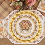 Thanksgiving-themed place setting with gold plates, turkey design, and decorative napkins on a plaid tablecloth.