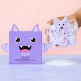 Purple monster-shaped bath sponge with a box on a pink background
