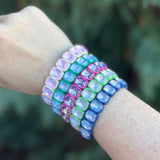 Multicolored beaded bracelet on a wrist with a blurred green background