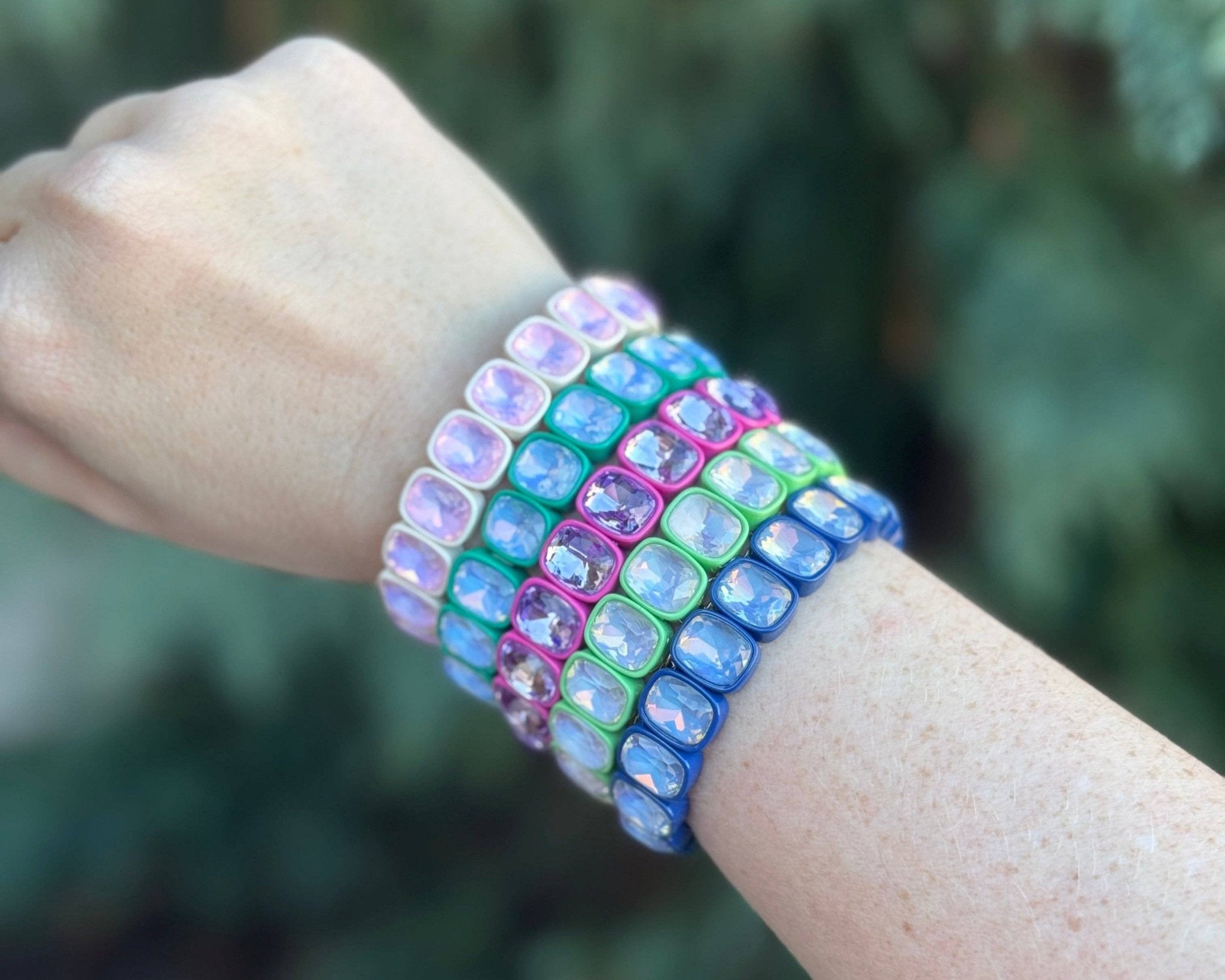 Multicolored beaded bracelet on a wrist with a blurred green background