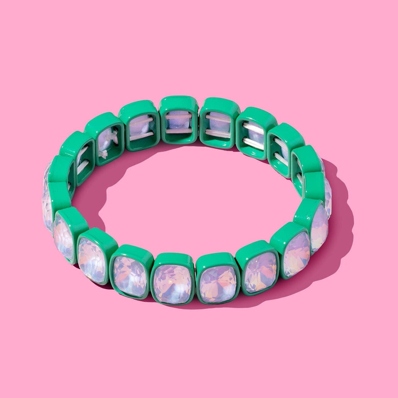 Green bracelet with clear stones on a pink background