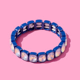Blue beaded bracelet with white accents on a pink background