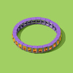 Bracelet with purple band and multicolored stones on a green background