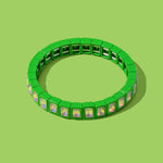 Green bracelet with small square charms on a green background
