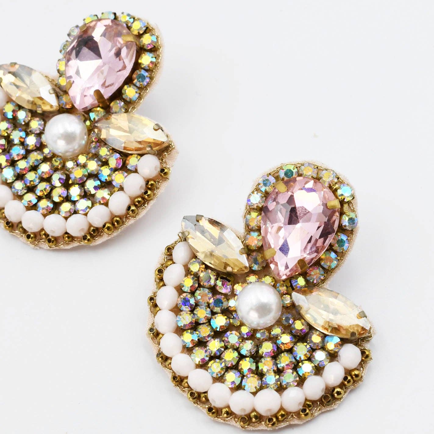 Jewelry earrings with pink, white, and gold elements on a white background