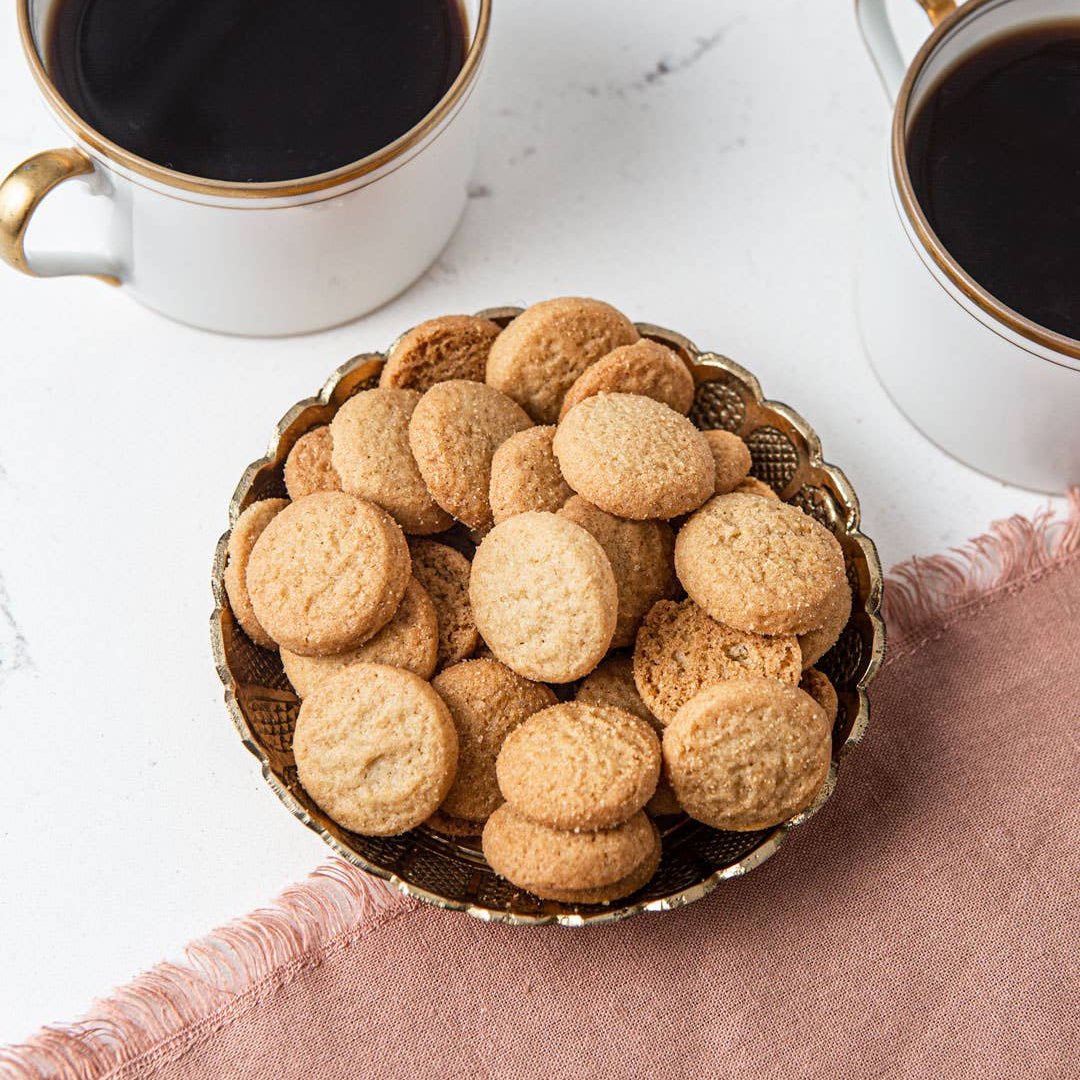 Bowl of cookies with two cups of coffee on a marble surface