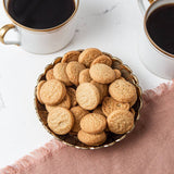 Bowl of cookies with two cups of coffee on a marble surface
